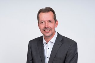 Das Bild zeigt Patrick Hartmann, einen Mann mit kurzem, grauem Haar.