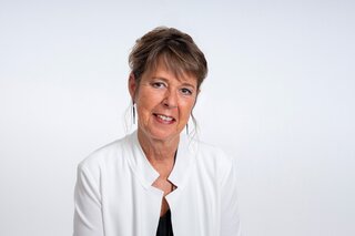 Das Bild zeigt Manuela Fiebig, eine Frau mit kurzem, braunem Haar, die freundlich lächelt.