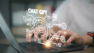 Auf dem Bild sieht man Hände, die auf einem Laptop tippen. Über dem Laptop schwebt eine grafische Darstellung mit dem Text "CHAT GPT".