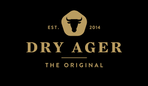 Das Bild zeigt das Logo von "DRY AGER". Es ist in goldener Schrift auf schwarzem Hintergrund und beinhaltet ein Rind-Symbol.