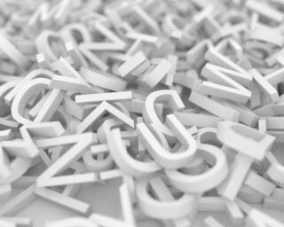 Das Bild zeigt eine chaotische Ansammlung von weißen Buchstaben, die zufällig und übereinander gestapelt liegen, auf einem hellen Untergrund.