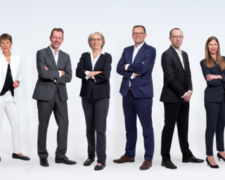 Das Bild zeigt eine Gruppe von zehn Personen in formeller Kleidung, die in einer Reihe stehen und in die Kamera lächeln. Dies sind die Berater der HWK Frankfurt-Rhein-Main.